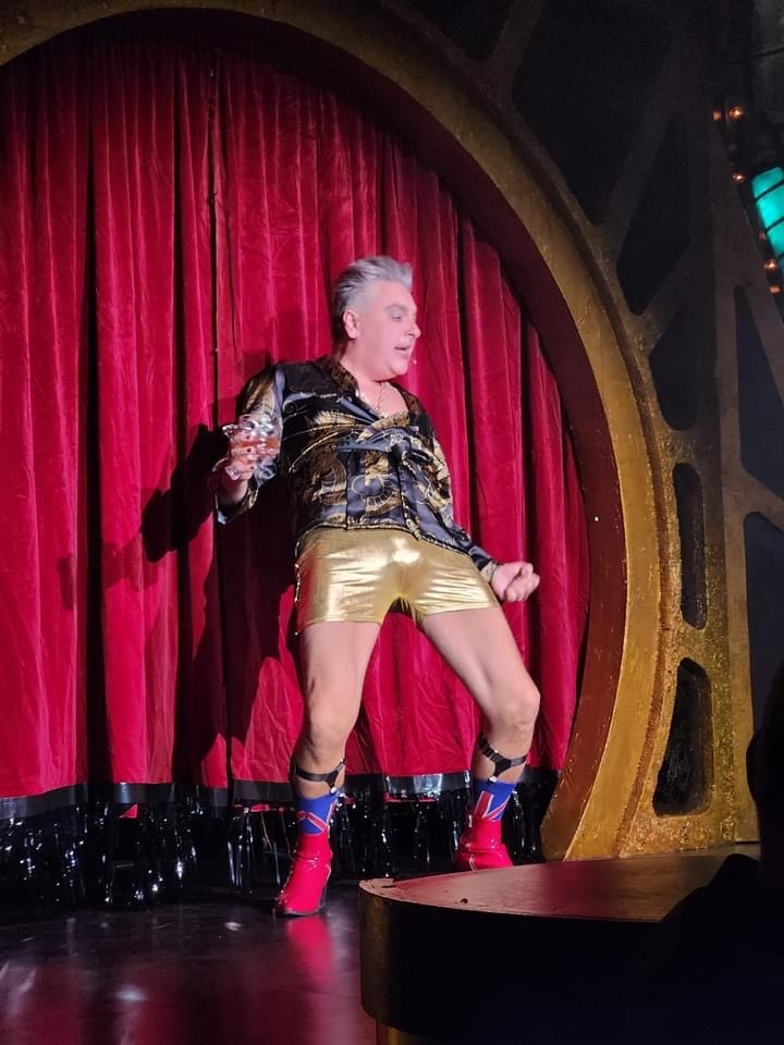 Saucy Jack and the Space Vixens 2022 — performer in gold shorts on stage